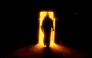 Human silhouetted in a doorway against amber fiery shades by Xusenru