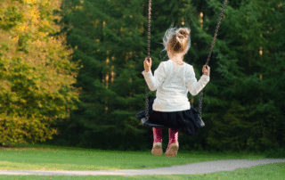 Young girl swinging in a green park