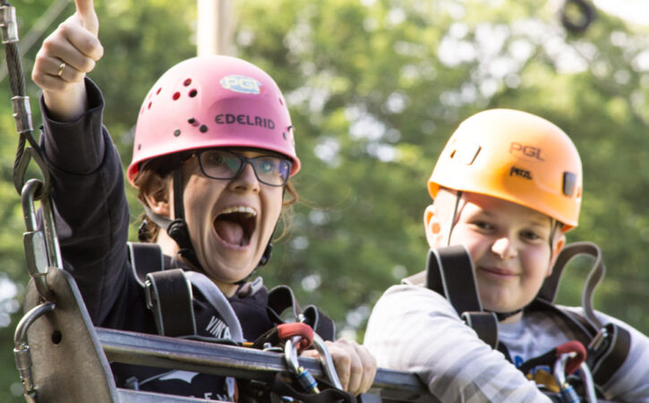 Two children hanging on a swing on an obstacle course