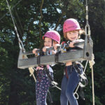 2 girls in a giant swing at an outdoor adventure park