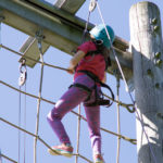 Child climbing a high obstacle net