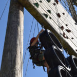 Vertical challenge course child clambering through a tyre