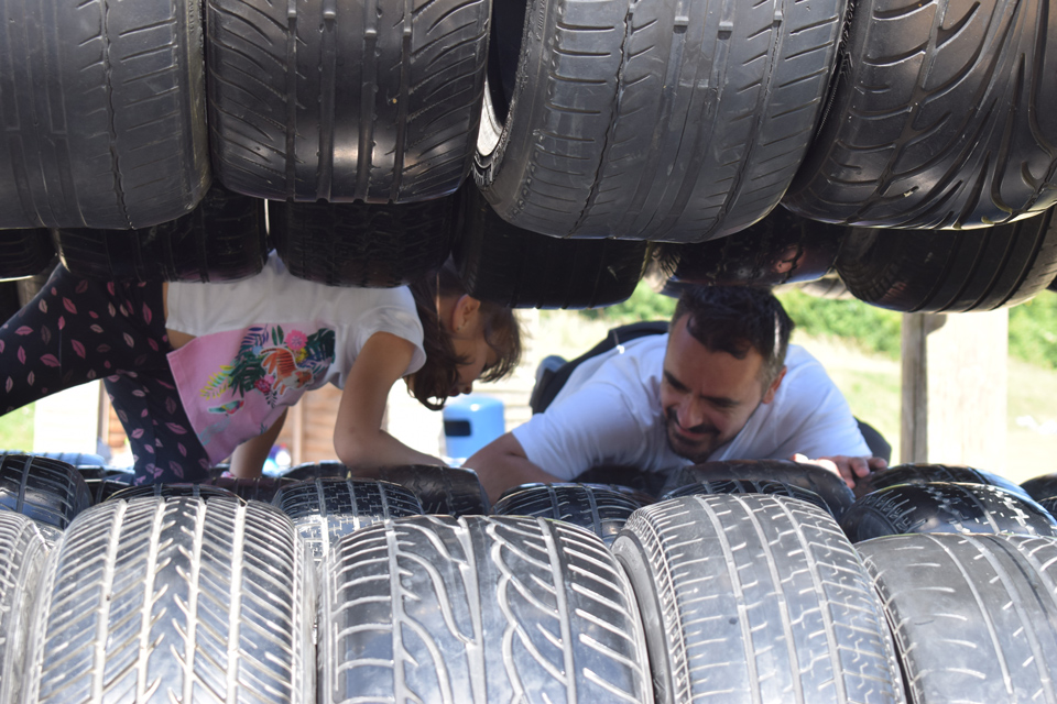 parent and child climbing through obstacle course tyres