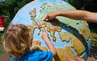 Small boy being shown the world on a large globe