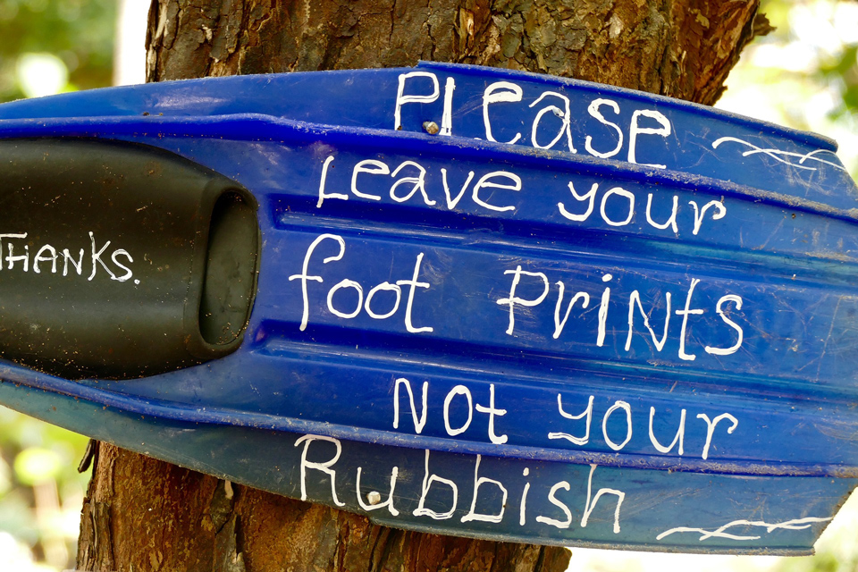 Leave footprints not rubbish written on piece of plastic stuck in a tree