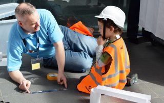 Man working on the floor with a child dresses as a mini engineer