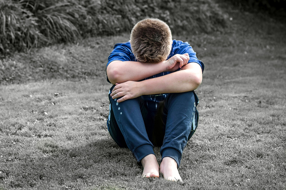 Boy sitting with his head in his arms