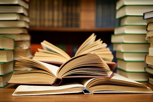 Piles of books on a desk with books opened piled on top of each other