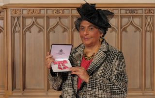 Professor Valsa Koshy holding her MBE awarded by the Queen March, 2019