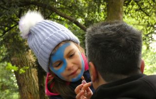 Girl applying "wode" facepaint to her father at the PPUK Be Curious Weekend 2019