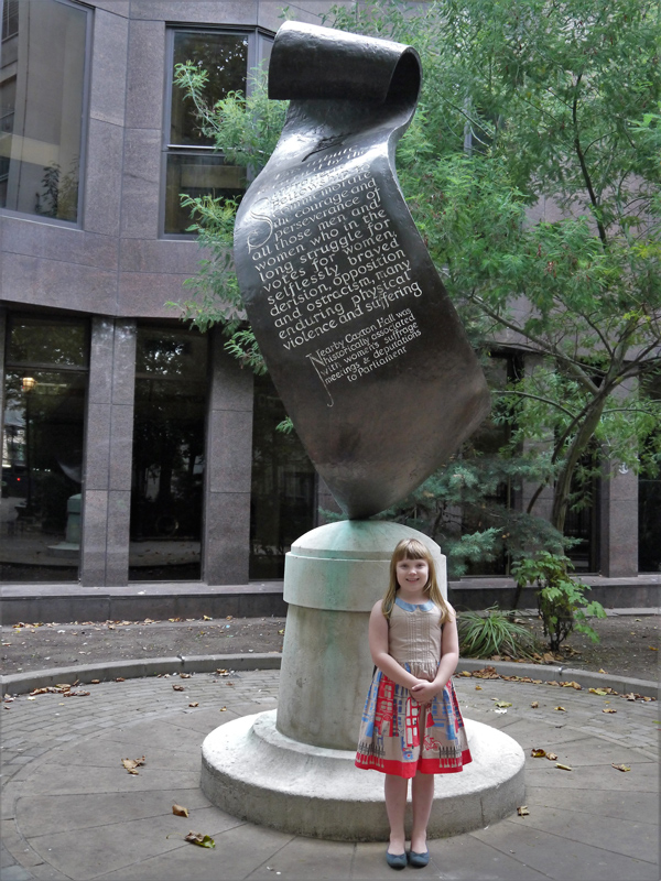 Girl standing underneath the Suffragette memorial in Christchurch Gardens