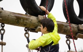 boy climbing an outdoor obstacle course