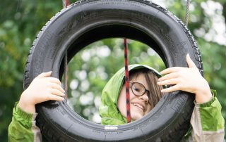 girl with face viewed through a tyre