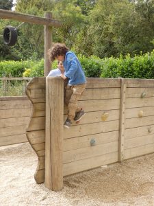 child climbing over an obstacle wall