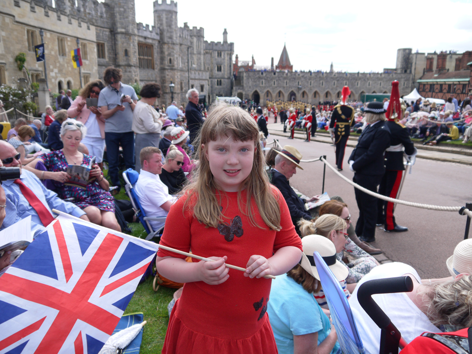 Girl holding a Union Jack flag in the crowd watching the procession at Garter Day 2019