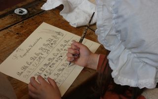 Child dressed in victorian mopcap doing copperplate handwriting practice