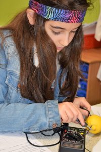 Girl measuring electricity generated by a lemon Potential Plus UK's BIG Family Weekend, 2019