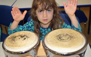young girl playing bongos at Potential Plus UK's BIG Family Weekend, 2019