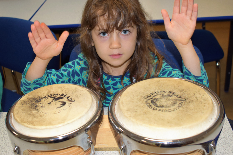 young girl playing bongos at Potential Plus UK's BIG Family Weekend, 2019