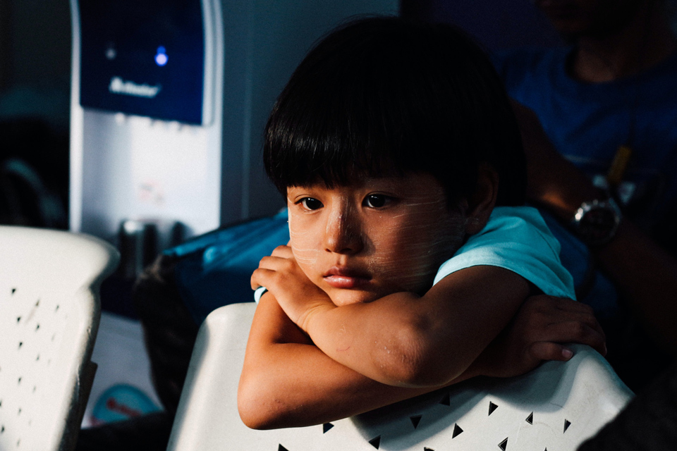 Child leaning on the back of a chair looking unhappy