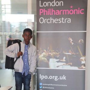 boy standing next to banner for London Philharmonic Orchestra