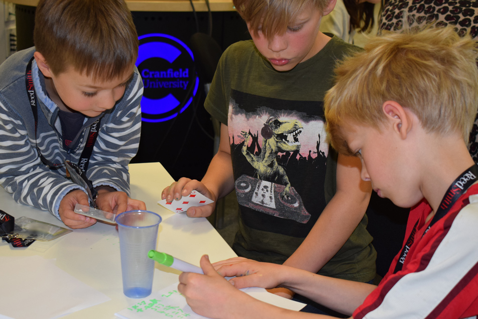 three boys around a table taking part in an activity