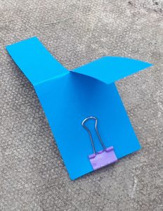 A paper helicopter with a bulldog clip weight