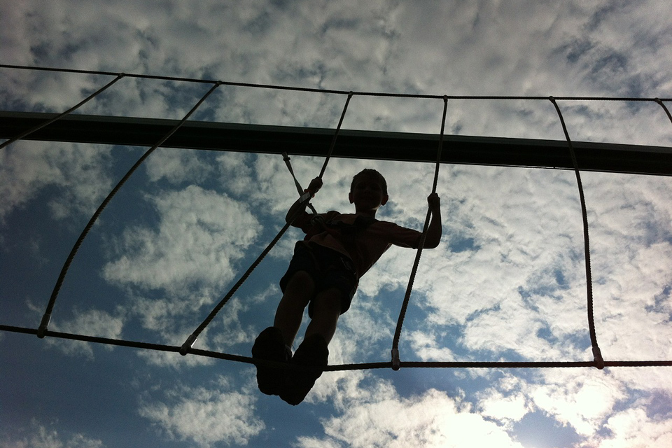 Boy silhouetted against the sky on a highwire