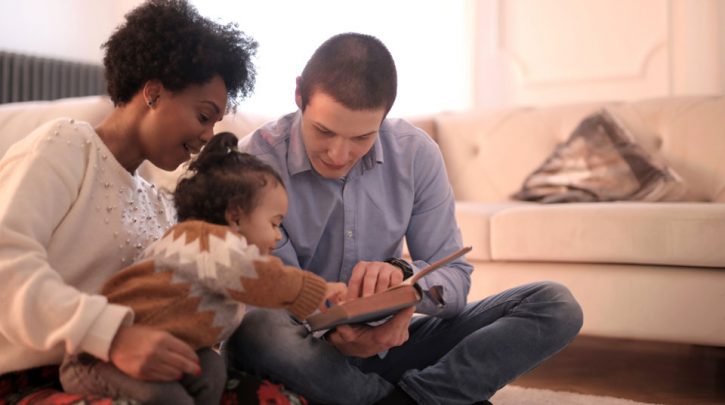 Family sitting on the floor looking at a book