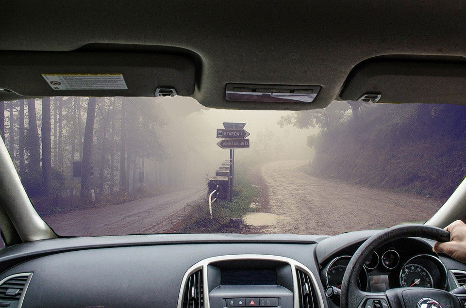 Looking through the dashboard of a car and seeing a misty road with choice of routes