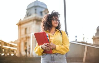 female student holding a folder standing outside university