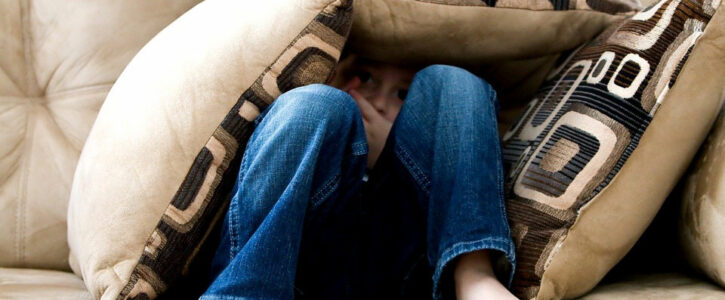 Boy hiding in cushions on the sofa