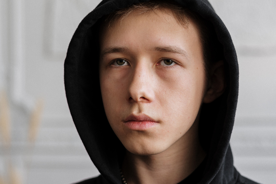 Boy wearning a hoodie looking into the distance with a solemn expression