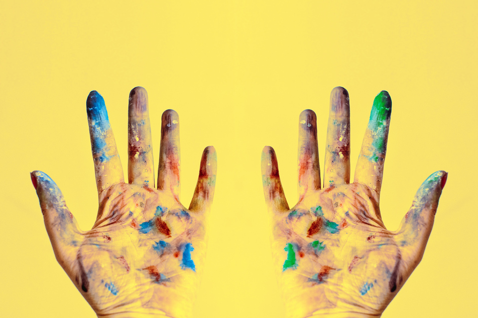 Photo of two hands covered in paint