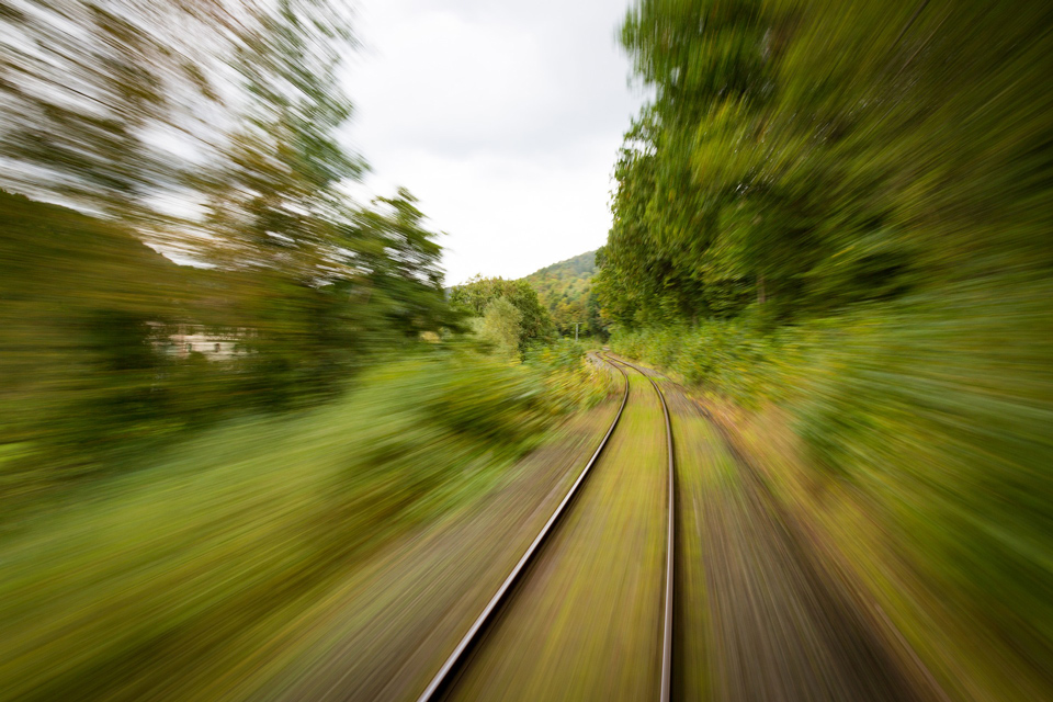 Photo of a train track with blurred scenery giving the impression of speed
