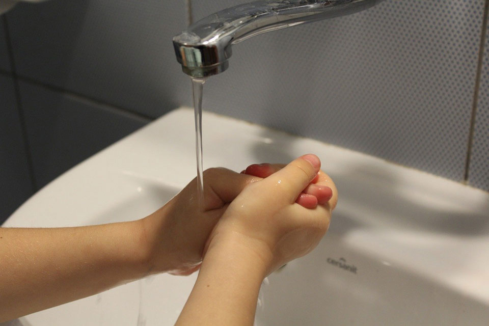 child washing hands under running tap