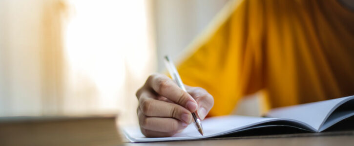 Hand of an adult holding a pen writing in a booklet