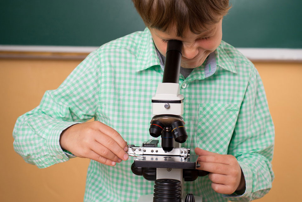 boy looking down a microscope