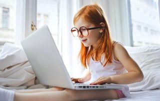 Girl sitting on a bed looking at a laptop