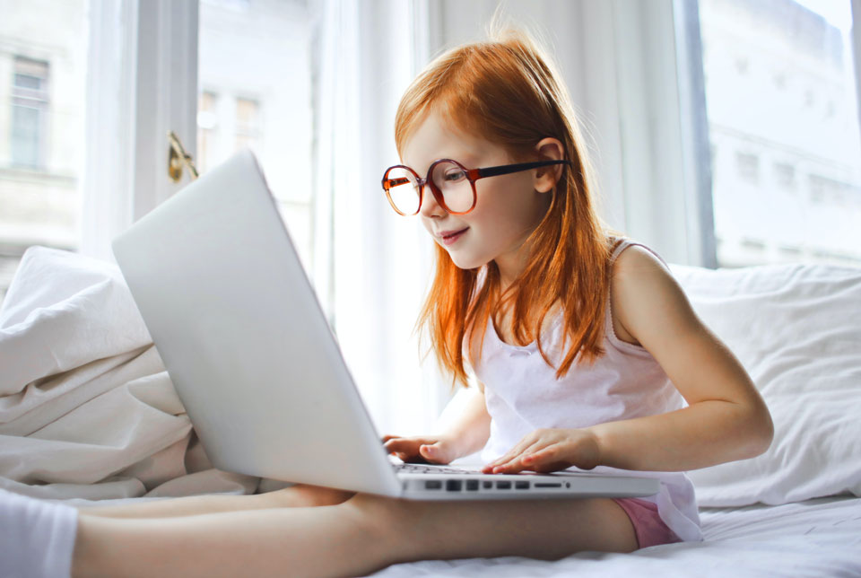 Girl sitting on a bed looking at a laptop