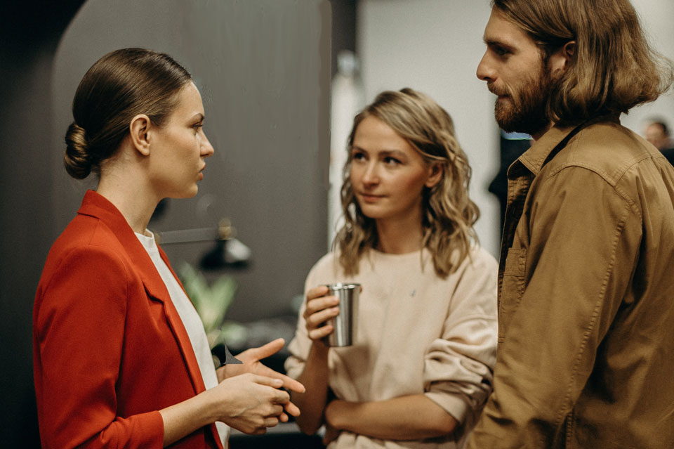 three adults standing talking