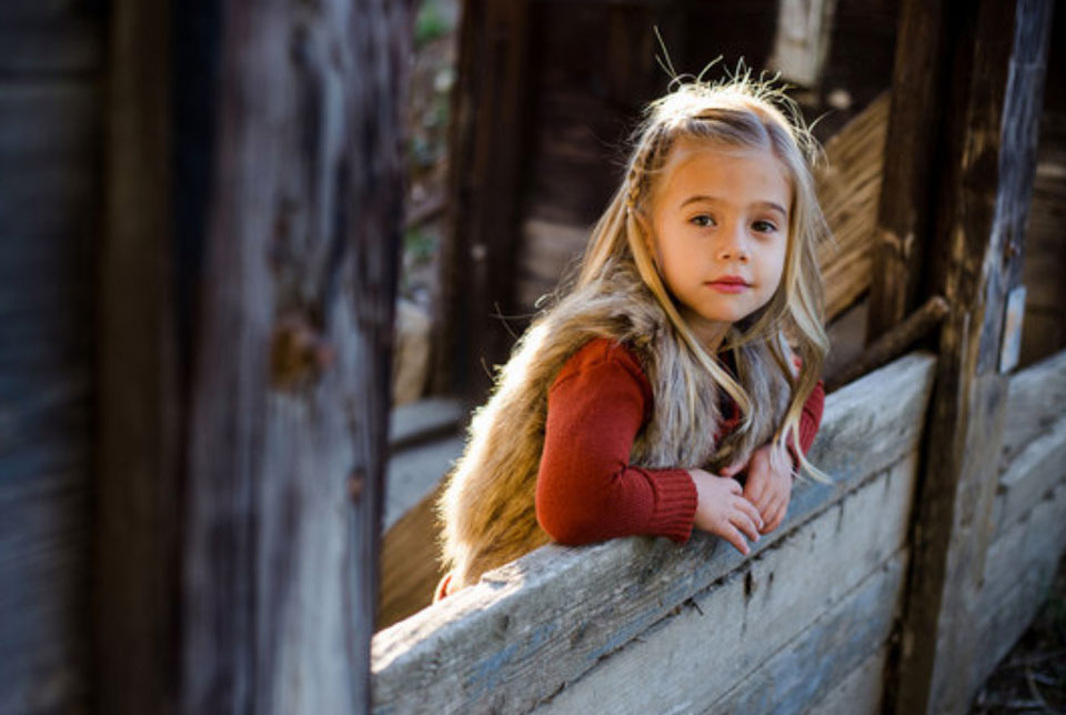 Young girl leaning against a wooden fence