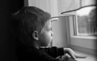 Mono photo of a boy staring out of the window