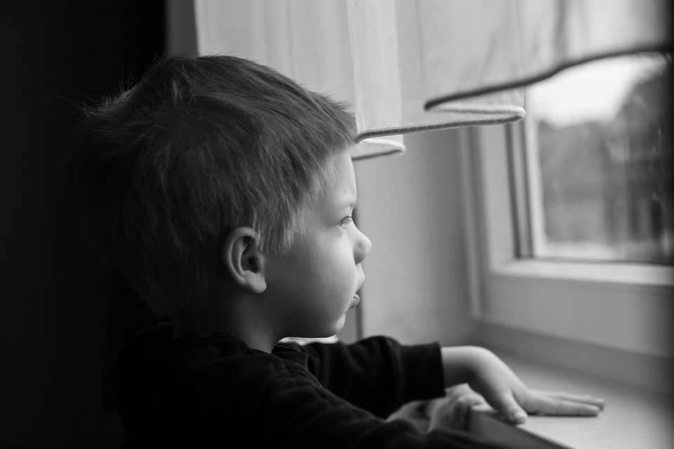 Mono photo of a boy staring out of the window