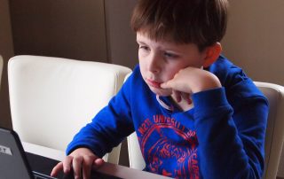 Boy sitting in front of a laptop looking sad