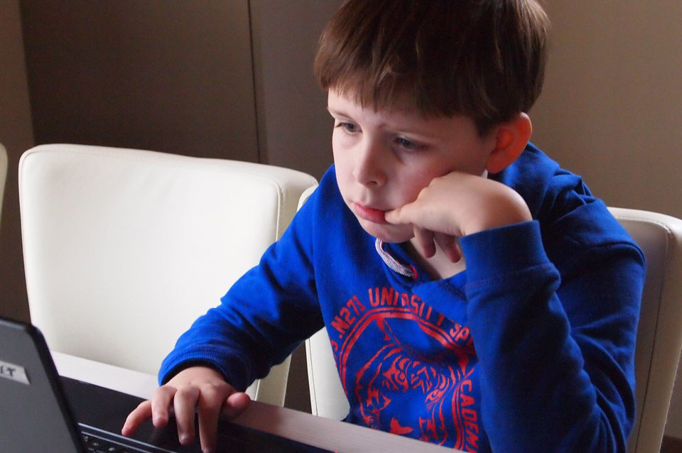 Boy sitting in front of a laptop looking sad