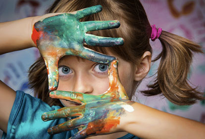 Child holding up painted hands used to frame face