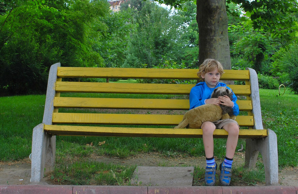 lonely child sitting on a park bench