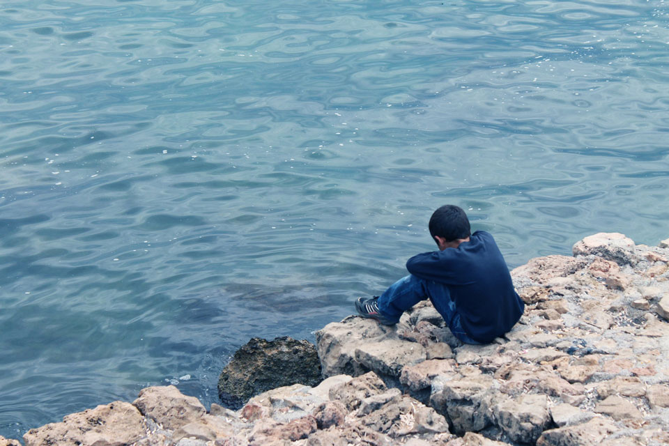 Child sitting on the edge of a stone jetty alone