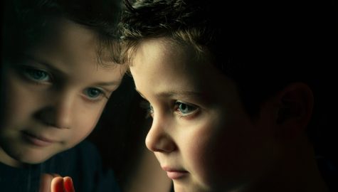 Child looking out of the window, with face reflected in the window